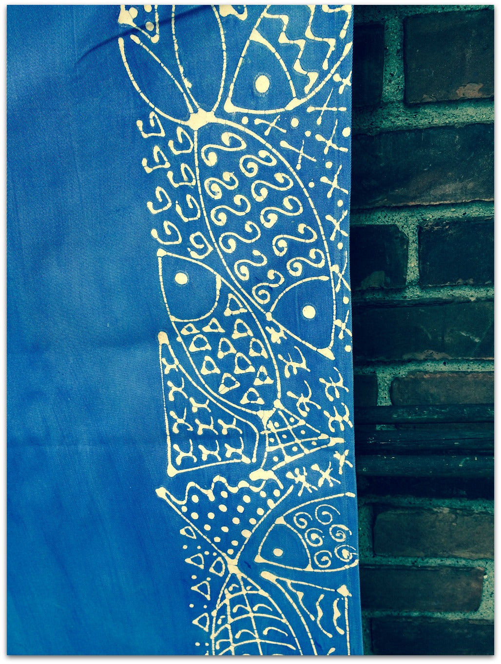 Photo showing the detail of the Blue Fish table runner.  Blue background with fish and a pattern in white down the edge. 